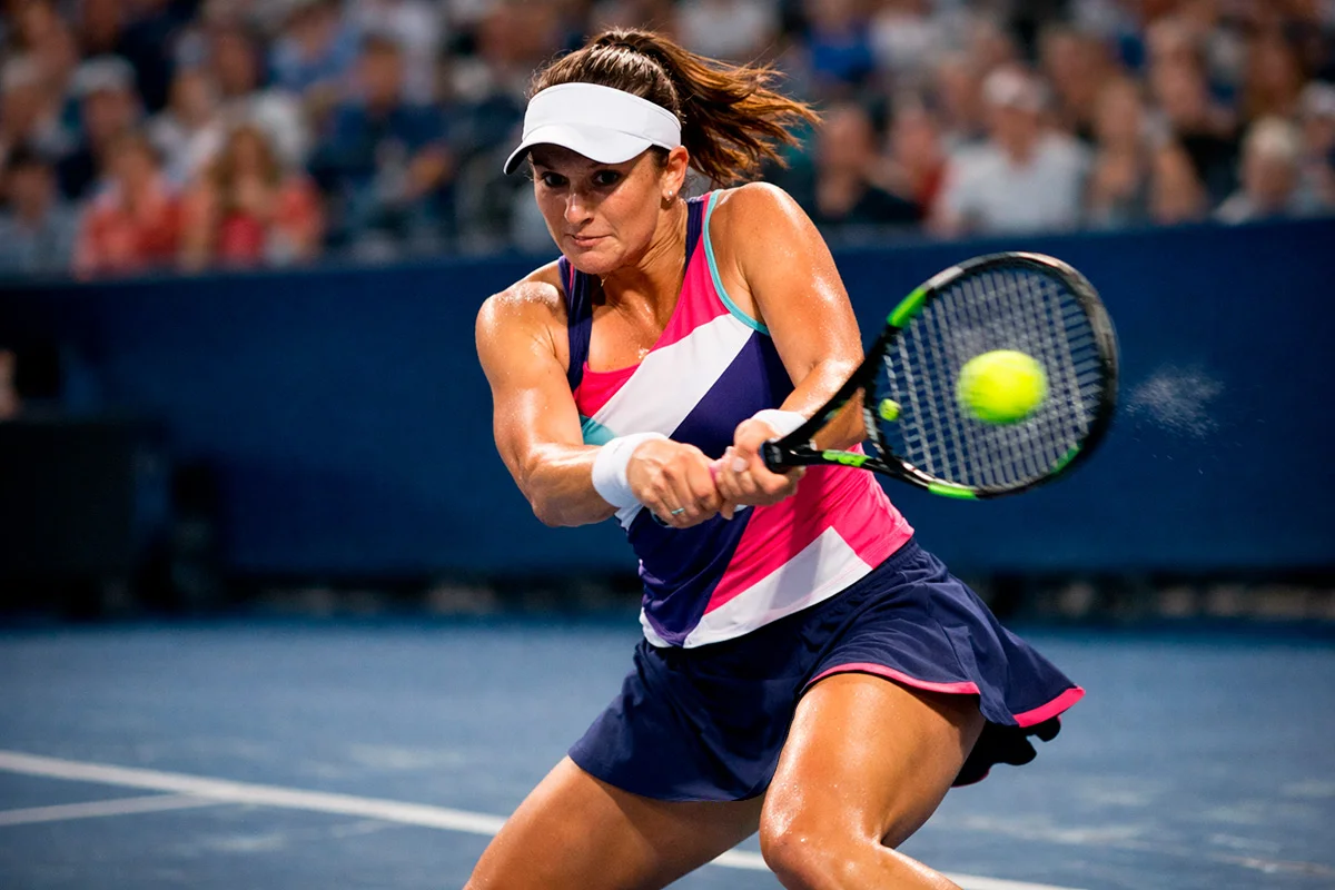 Tennisspielerin bei einem kraftvollen Rückhandschlag auf einem Hartplatz